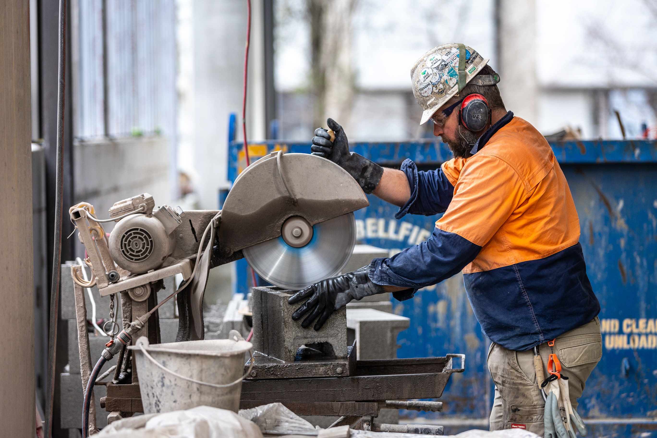 Labour Hire protective gloves man cutting concrete brick with an electric saw ear protection safety glasses safety gloves building site blue-collar worker building clothing construction worker metalworking outdoor person power saw technician tool workwear hard hat high vis vest labour hire. cutting bricks