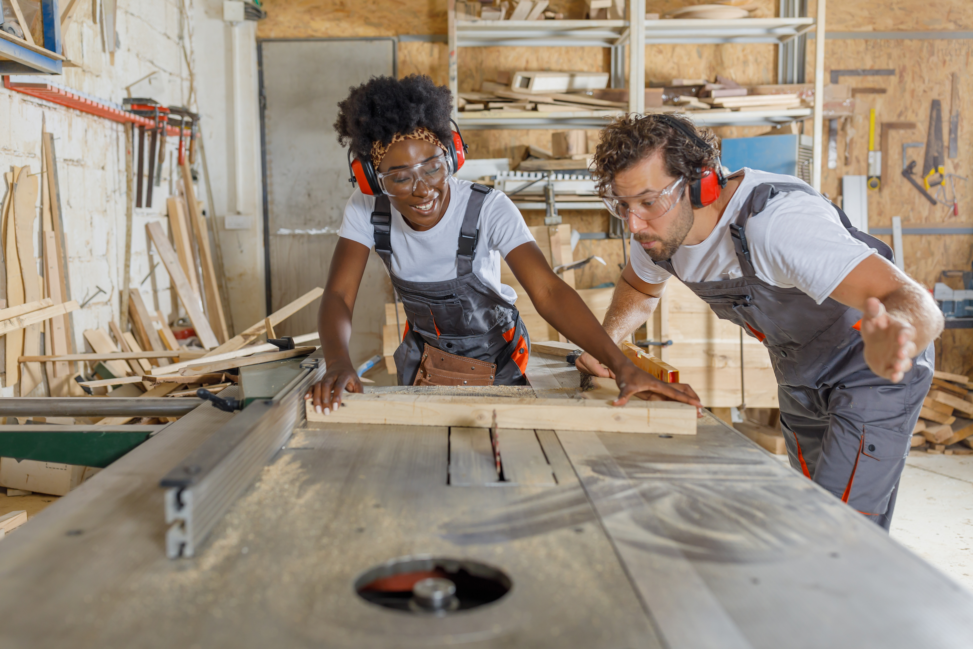 cabinet maker woodwork sawing electric saw mentor mentoring Labour Hire factory indoors wood cutting young woman cutting timber with electric saw guidance instructions artisan blue-collar worker carpenter clothing person tool carpentry labour hire