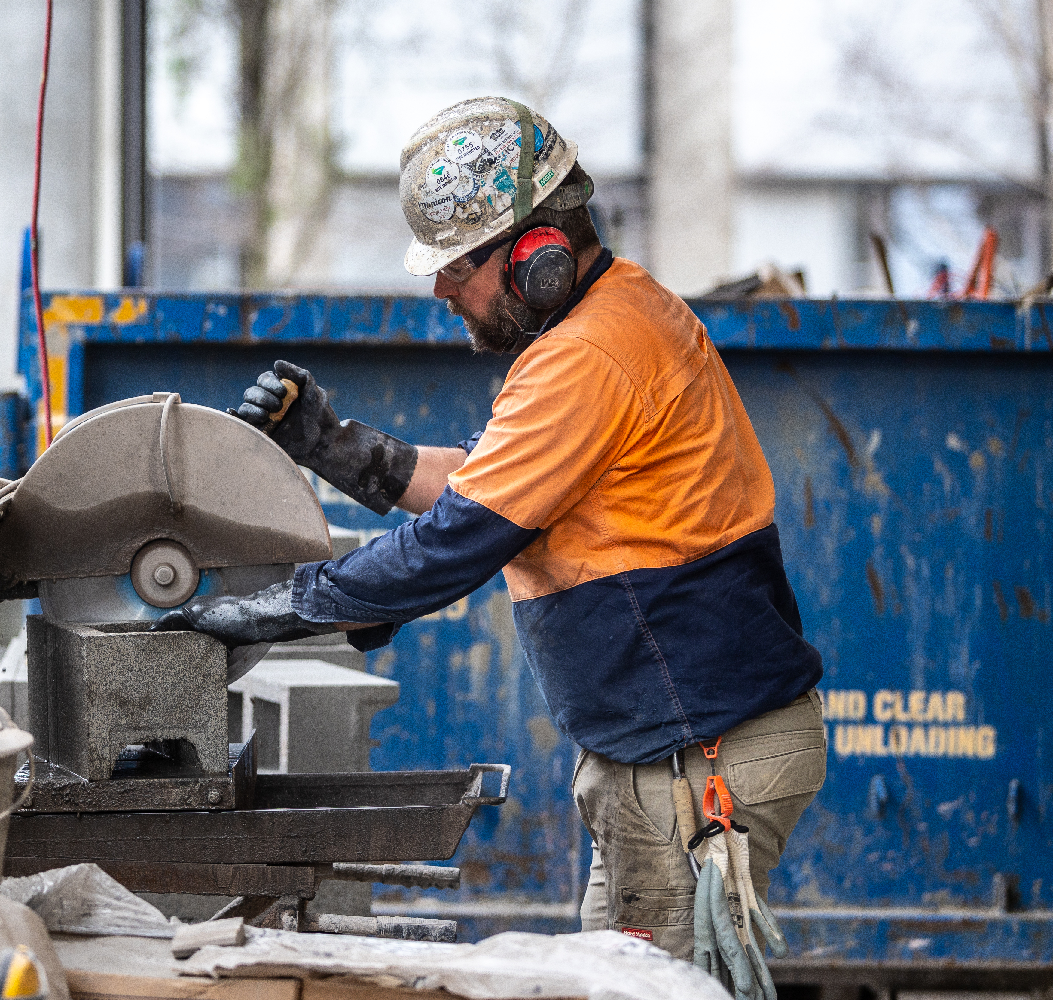 construction worker cutting concrete brick with electric saw building site man indoors safety glasses ear protection protective gloves blue-collar worker clothing helmet metalworking outdoor person power saw technician tool workwear employers construction worker labour hire window high vis vest tiles hardhat